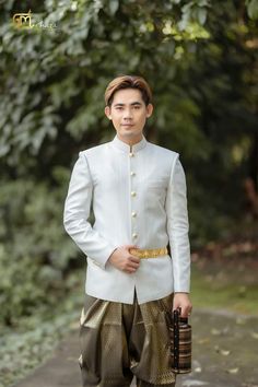 a young man dressed in white and gold is posing for the camera with his hand on his hip