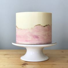 a white and pink cake with gold trim