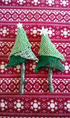 two knitted christmas trees sitting on top of a red and white blanket