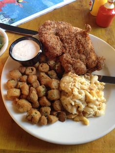 a white plate topped with fried food next to a bowl of dipping sauce and spoon