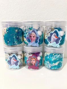 there are six plastic containers with frozen princess magnets on the top one is filled with snowflakes