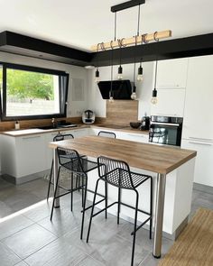 a kitchen with an island table and bar stools next to the counter top in front of a window