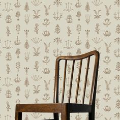 a wooden chair sitting in front of a wallpapered with flowers and plants on it