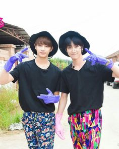 two young men wearing purple gloves and black shirts standing next to each other in front of a building