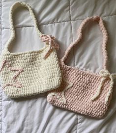 two crocheted purses sitting on top of a white bed next to each other