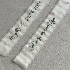 two white ribbons with embroidered words on them