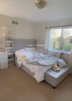 a bedroom with a large bed and white furniture in it's center area, next to a window