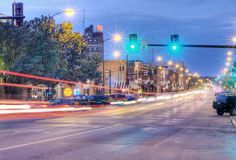 an empty city street at night with traffic lights and cars driving down the road in front of it