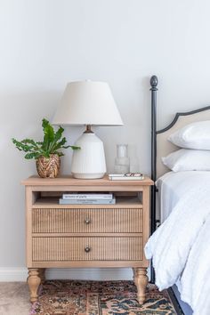 a bedroom with a bed, nightstand and lamp on the side table in front of it