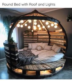 a bed made out of pallets with lights hanging from the ceiling and pillows on top