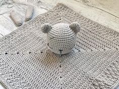 a crocheted teddy bear sitting on top of a rug