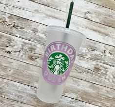 a starbucks cup sitting on top of a wooden table with a straw in the cup