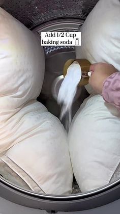 someone is pouring something out of the back of a washing machine with white pillows on it