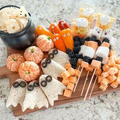 an assortment of halloween treats on a cutting board with oranges, blackberries and marshmallows