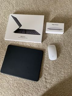 an apple laptop and mouse sitting on the floor next to it's packaging box