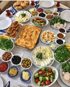 a table topped with lots of plates and bowls filled with different types of food next to each other