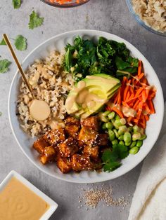 a white bowl filled with rice, meat and veggies next to bowls of sauce