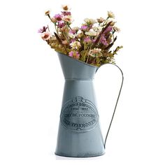 a metal pitcher filled with pink and white flowers