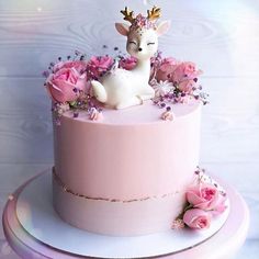 a pink cake decorated with flowers and a deer figurine sitting on top of it