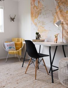 a desk with two chairs and a map on the wall behind it in a white room