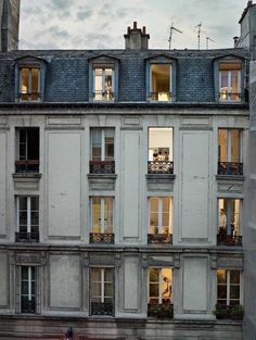 an apartment building with lots of windows and balconies on the top floor at dusk