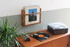 a record player sitting on top of a wooden table next to a plant and an album