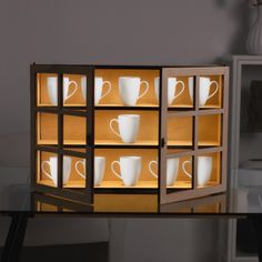 a lit up shelf with coffee cups in it