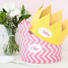 two paper crowns sitting on top of a table next to vases with flowers in them