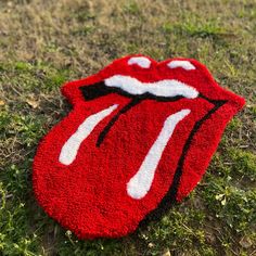 a red rug with the rolling stones on it is laying in the grass and has its tongue painted white