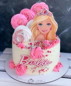 a birthday cake decorated with pink frosting and barbie doll on top, sitting on a table