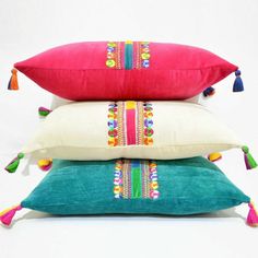 three pillows stacked on top of each other with tassels and pom poms