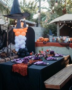 a table set up for halloween with balloons and witch hats on it, along with other decorations