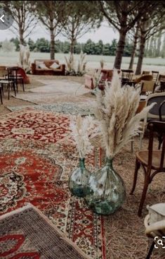 an area with chairs, tables and rugs is shown in front of the trees