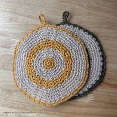 two crocheted coasters sitting on top of a wooden table