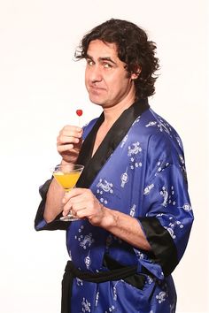 a man in a blue robe holding a drink