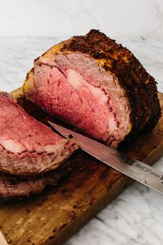 a large piece of meat sitting on top of a cutting board next to a knife