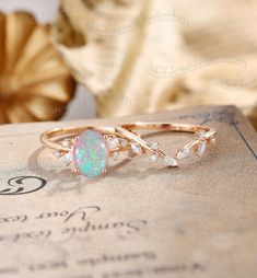 an opal and diamond ring sitting on top of a book