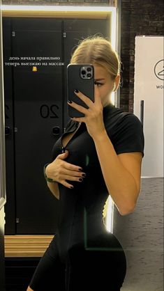 a woman taking a selfie in front of a mirror with her cell phone up to her face