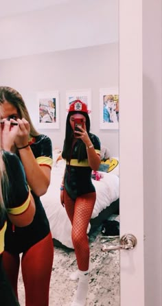 two women are taking pictures in the mirror while one woman is dressed as firefighter