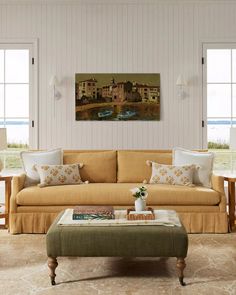 a living room filled with furniture and windows next to a painting hanging on the wall