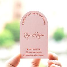 a person holding up a pink business card in their hand with the words ope algon on it