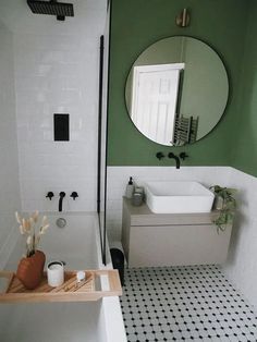 a bathroom with green walls and black and white flooring, including a bathtub