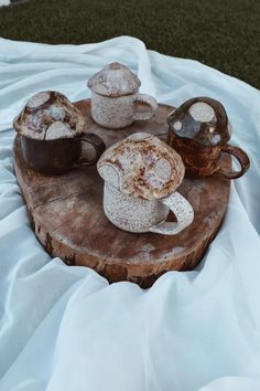 three coffee mugs sitting on top of a wooden table next to another cup and saucer