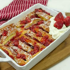 a strawberry french toast casserole with whipped cream and strawberries on the side