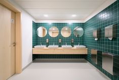 a public restroom with three sinks, mirrors and urinals on the wall next to each other