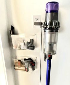 a purple and silver vacuum is hooked up to a wall with shelves on the side