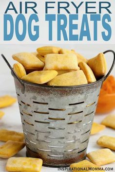 a metal basket filled with dog treats on top of a white table next to oranges