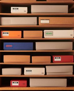 many boxes are stacked on top of each other in a wooden shelving unit that is filled with files and folders