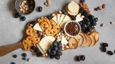 an assortment of cheeses, crackers, nuts and blackberries on a platter