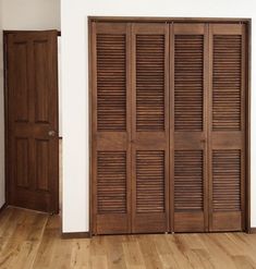 an empty room with wooden shutters on the doors and hard wood flooring,